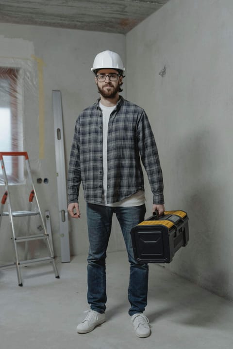 A Grace Vision technician in a hard hat carrying a toolbox on a site under renovation
